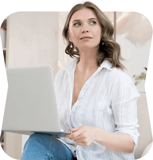 Beautician in a white shirt planning content on her laptop in a bright studio