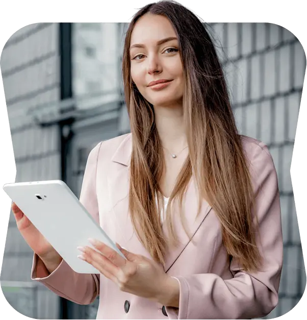 Real estate agent in a pink blazer holding a tablet outside a modern building
